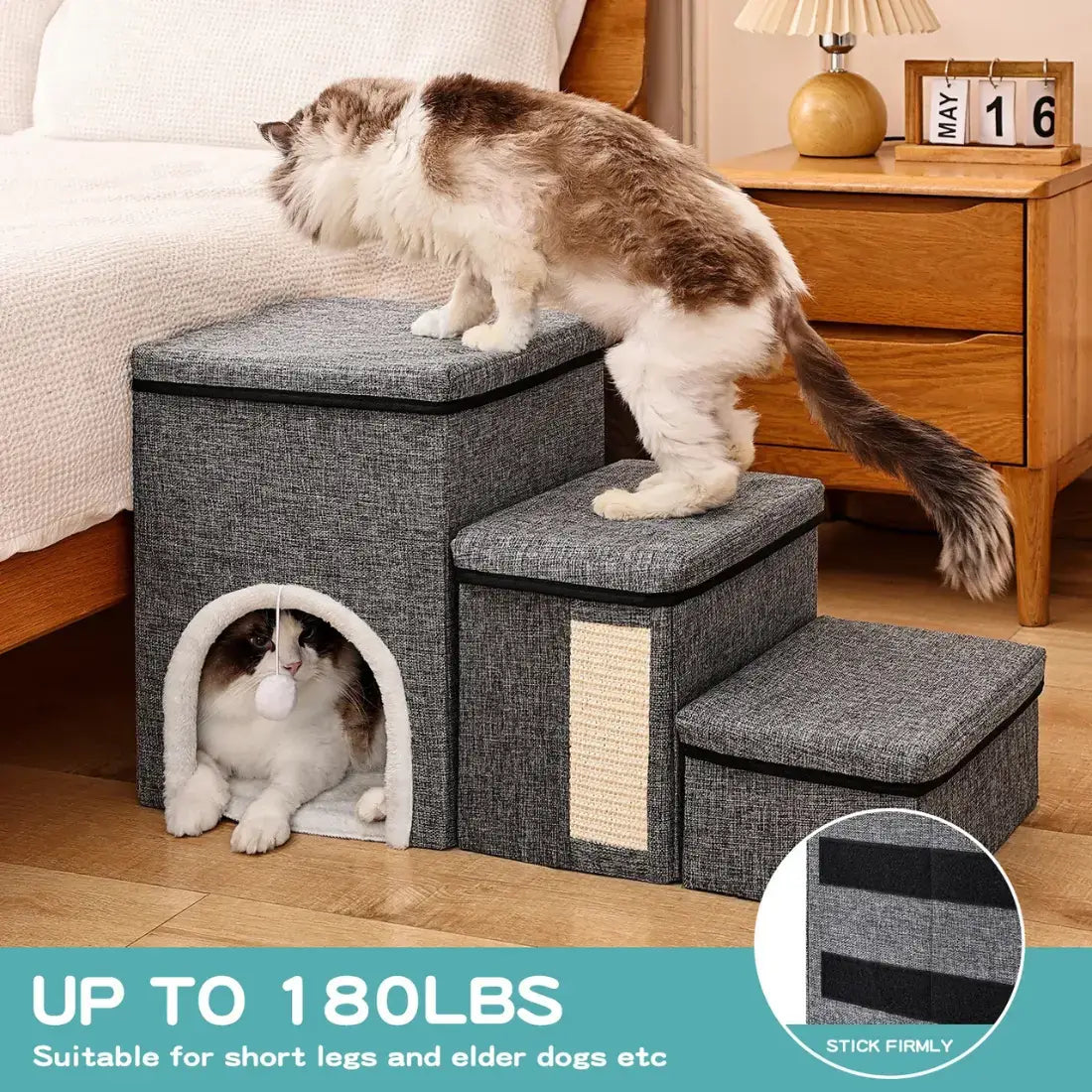 A three-step gray fabric cat staircase with an arched entryway and scratching panel, shown in a bedroom with two cats using it. Text at the bottom reads 'UP TO 180LBS Suitable for short legs and elder dogs etc'.