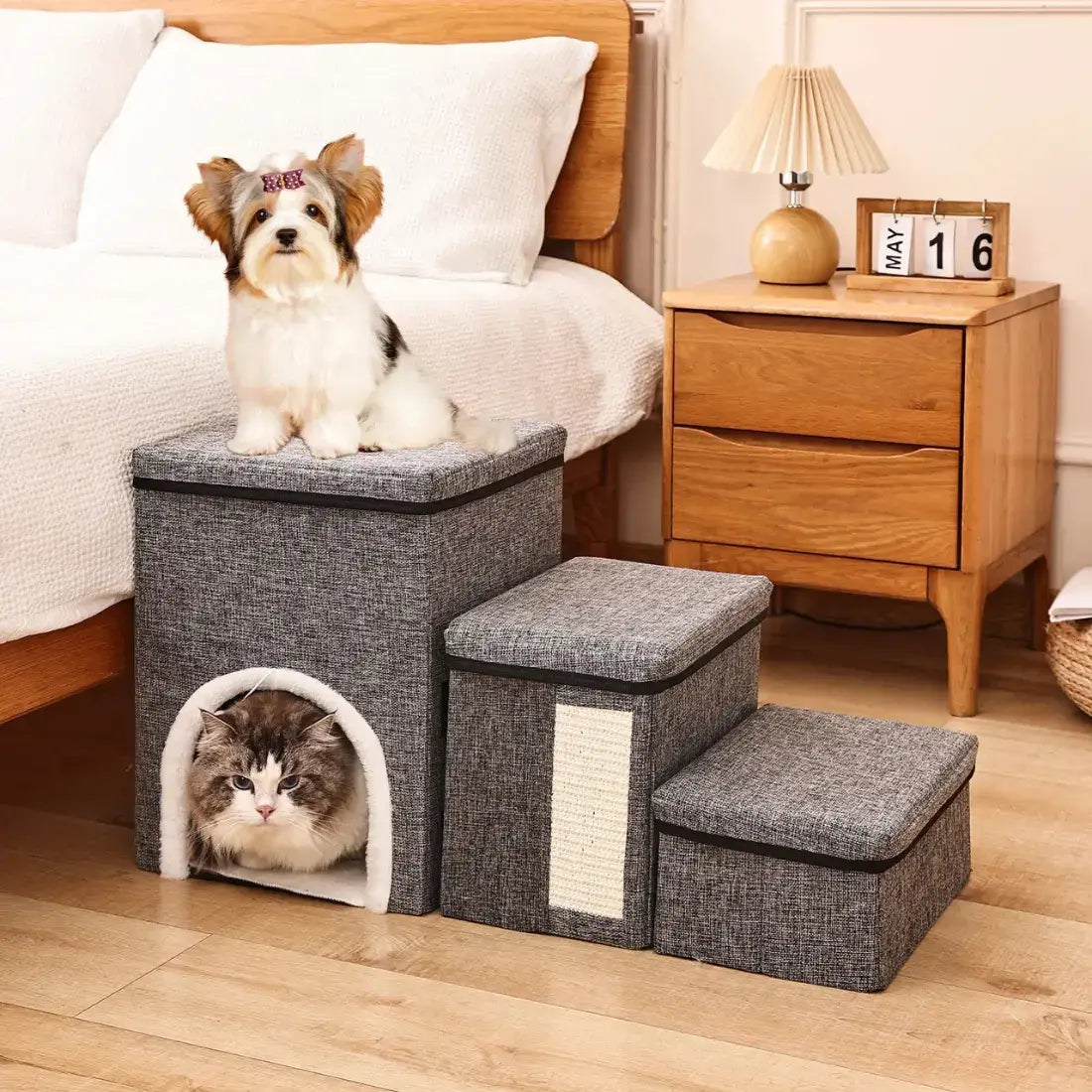 Pet steps with a dog and cat inside, placed on a wooden floor next to a bed and nightstand.