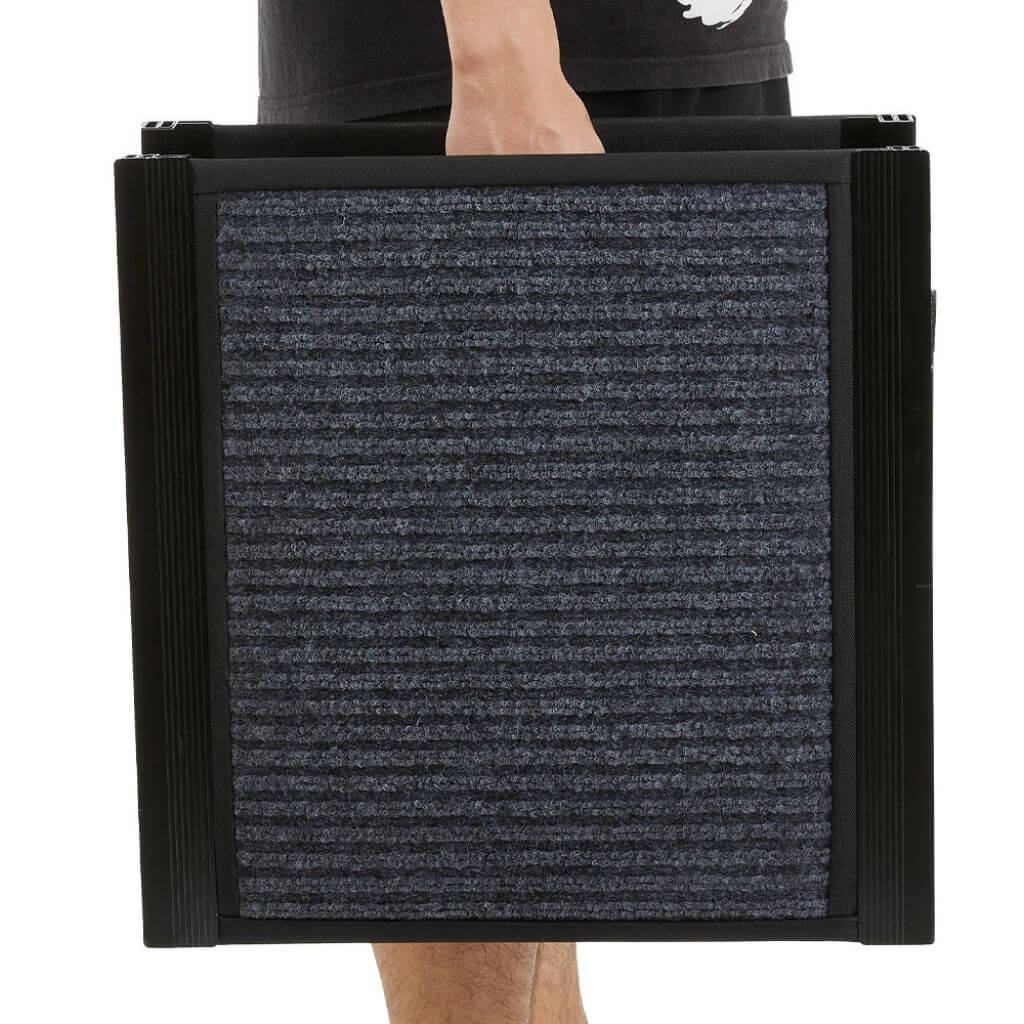 Person holding a large black folding dog ramp against a white background